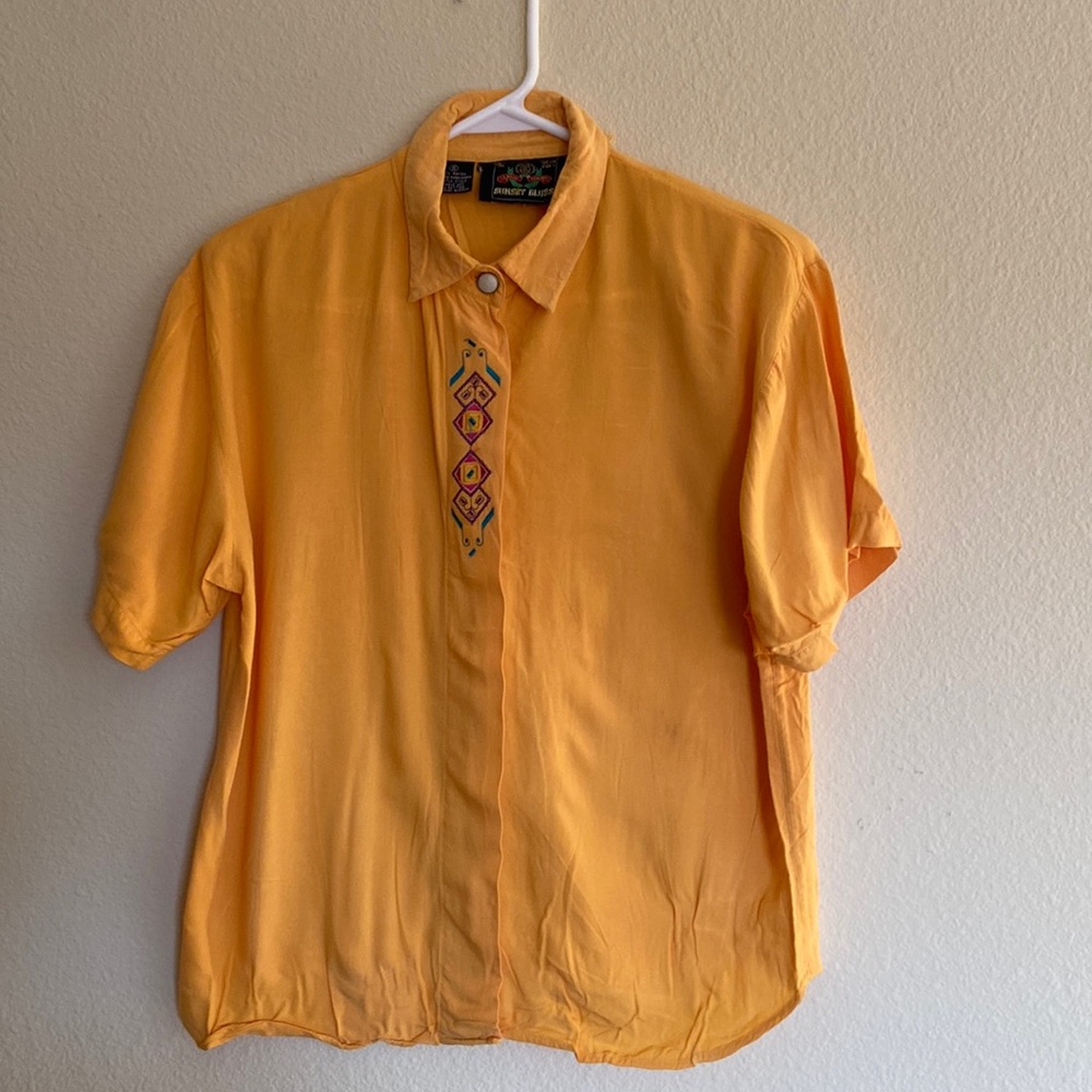100% rayon machine wash yellow shirt with embroided detail on the front. Size S